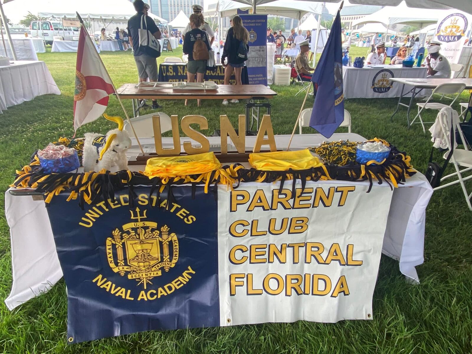 The club's banner and USNA flags displayed on a table at an outdoor gathering