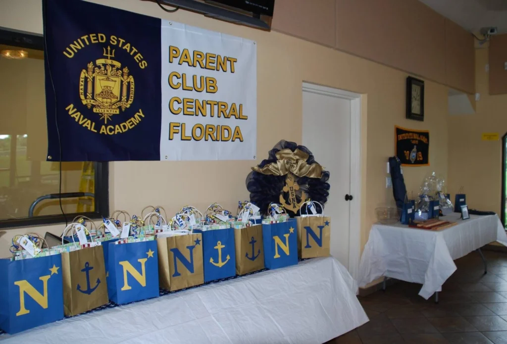 A row of gift bags lettered N and anchor, prepared for new parent families