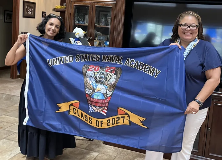 Two club members holding up the Class of 2027 crest flag at a club gathering