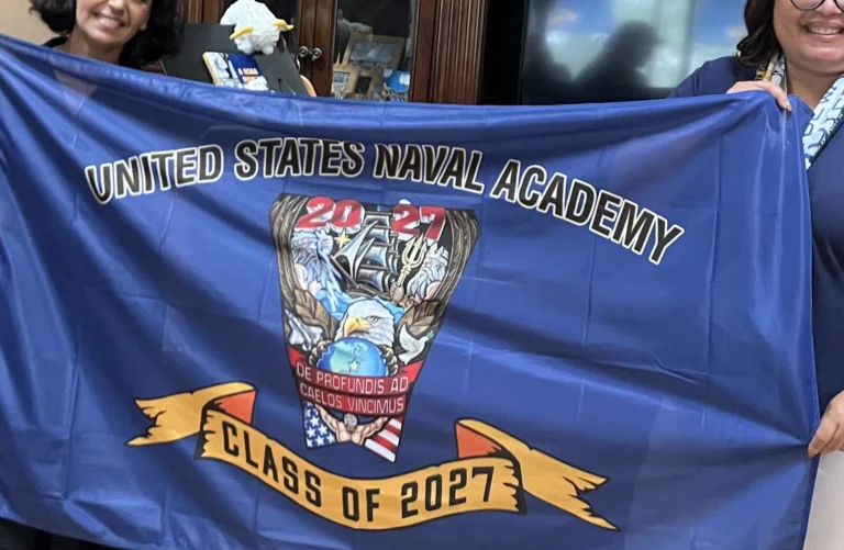 Two club members holding up the Class of 2027 crest flag